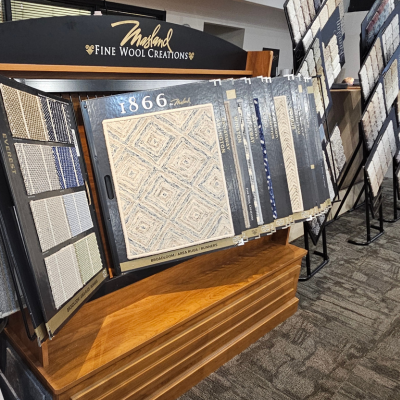 Masland Fine Wool Creations display featuring diamond-patterned rugs and various wool carpet samples on wooden bases.